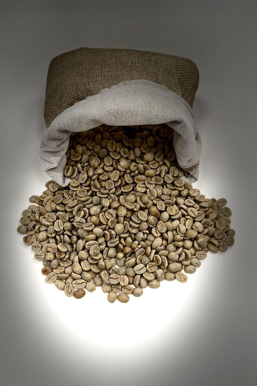 Green coffee beans beside a small jute sack